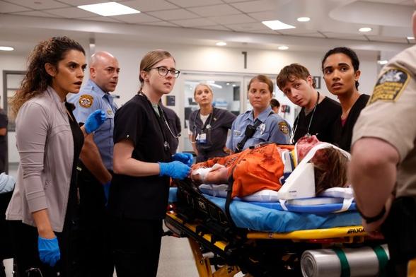 A group of doctors, nurses, and police officers around a body on a gurney; still from 'The Pitt'