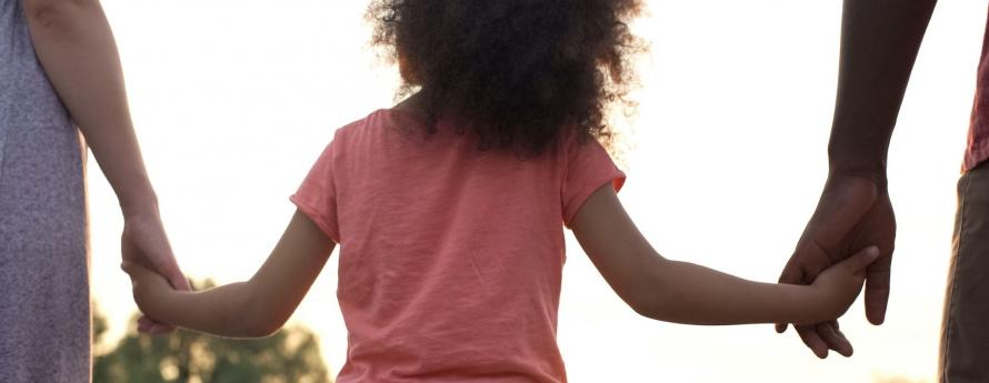 child holding both parents' hands while walking