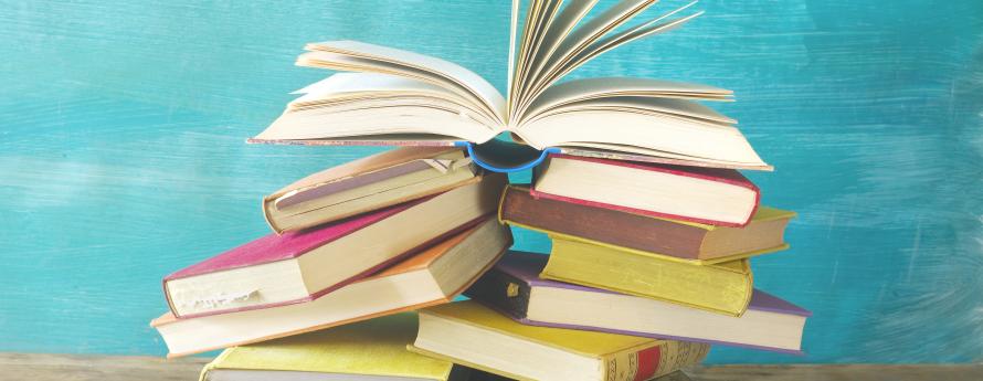 stack of books on a table, with open book on top
