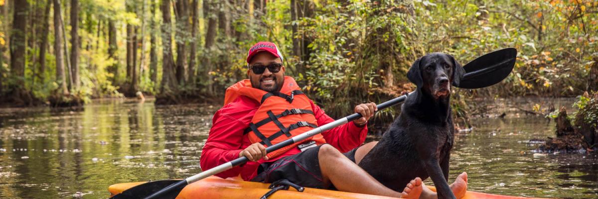Man kayaking with his dog
