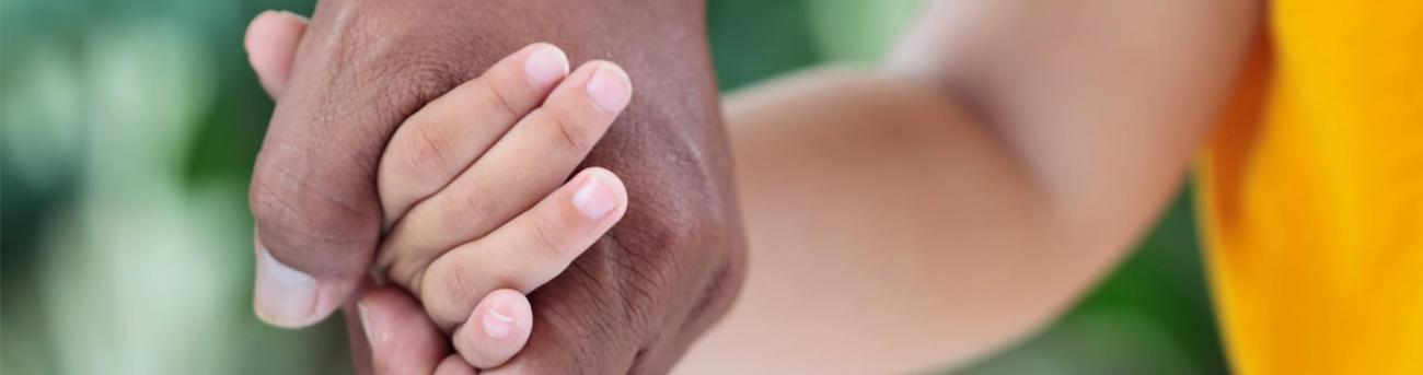 Parent holding a child's hand.