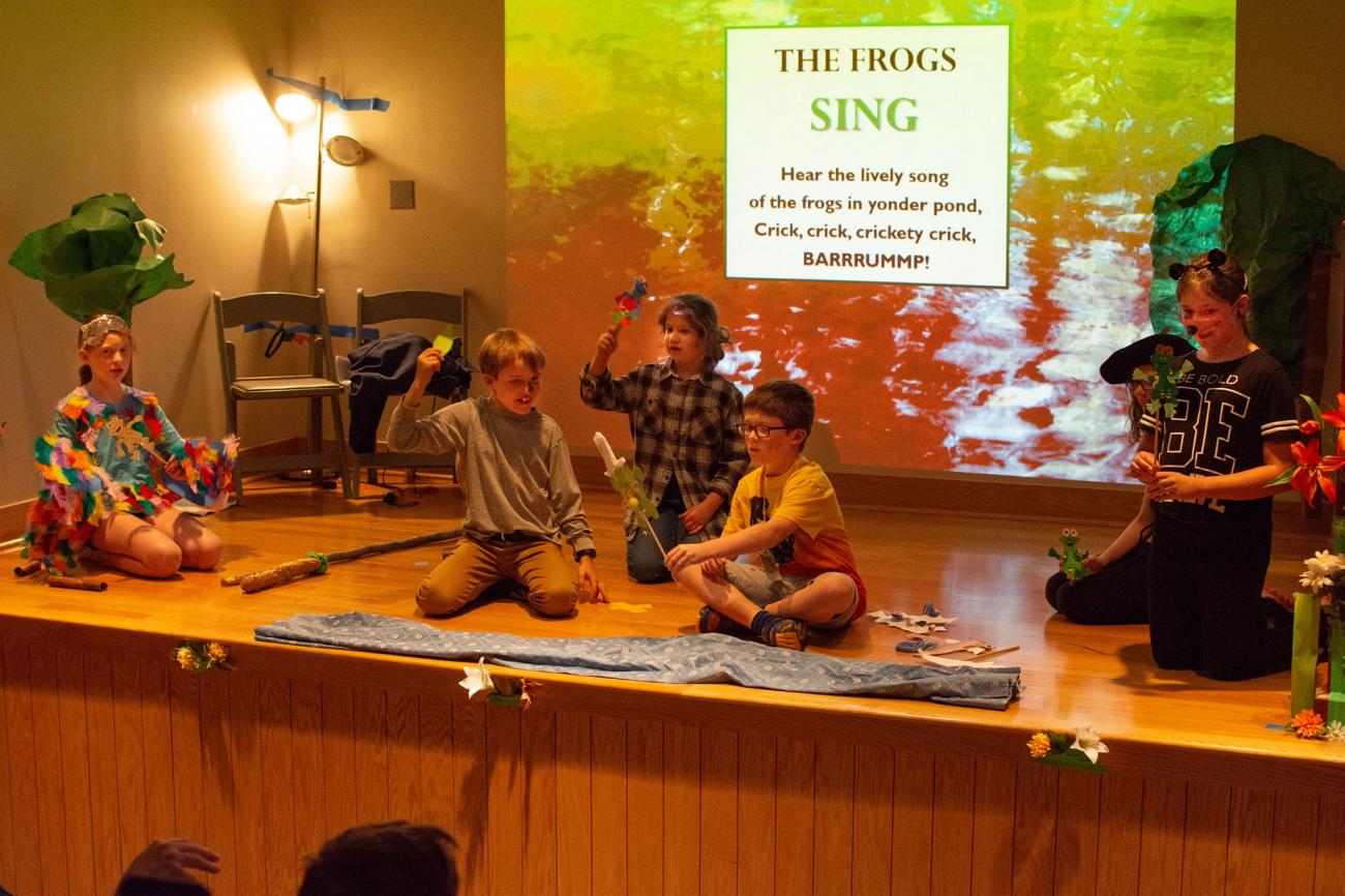 kids on stage in costumes with projected forest background