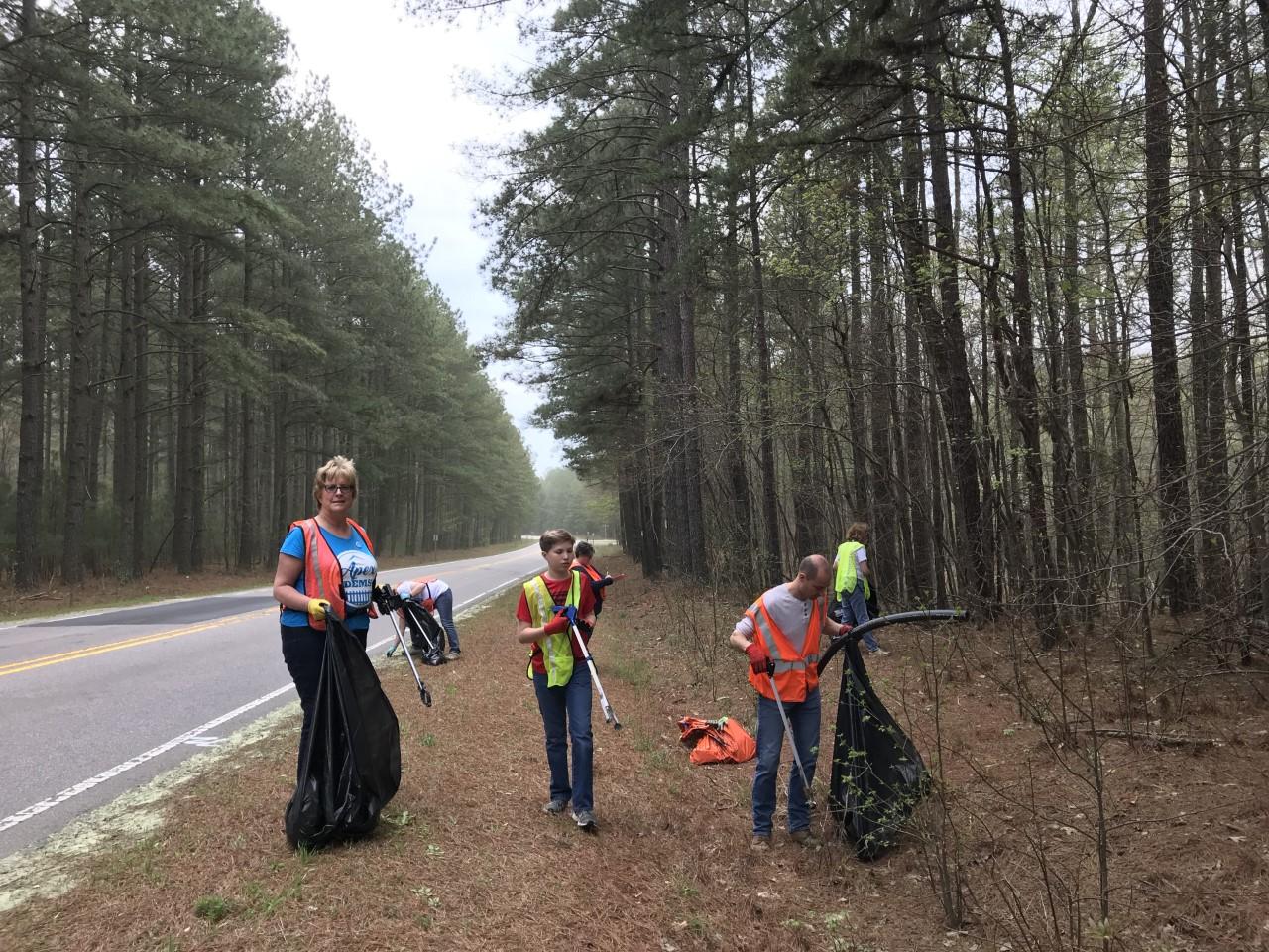 Photo of several volunteers picking up trash along the road shoulder