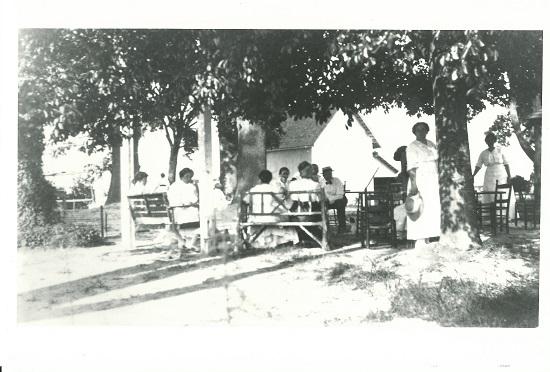Black and white image of a picnic at Oak View after 1900 with the carriage house in the background