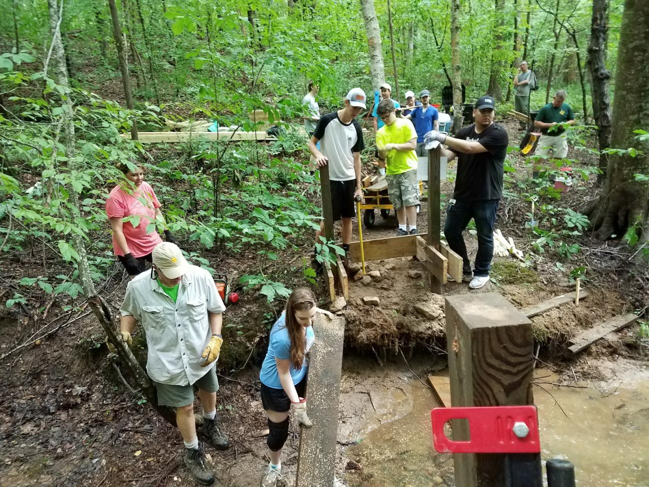 Eagle scout candidate and scout assistants installing a bridge on the Falls Lake Trail at Blue Jay Point