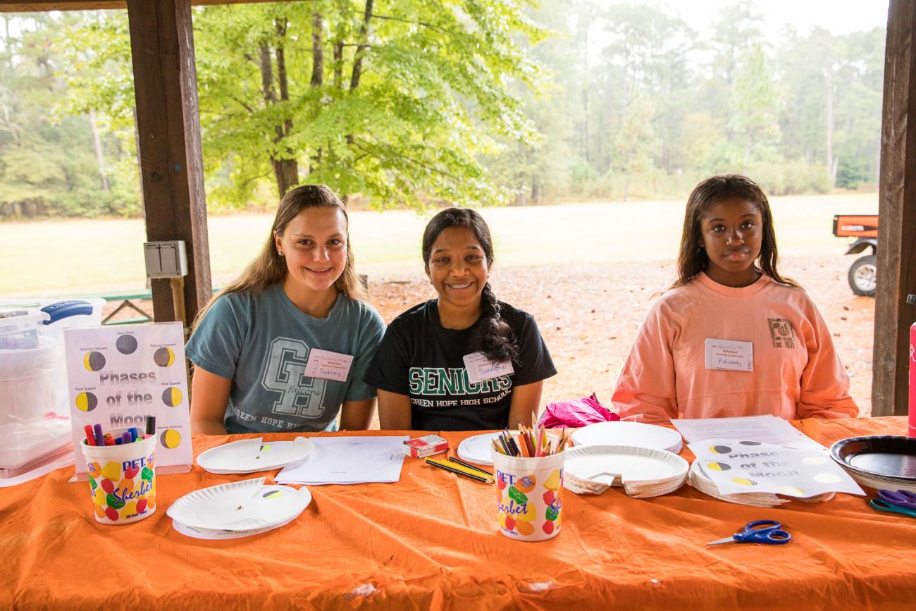 Photo of 3 volunteers assisting at a craft table at Haunting at Harris