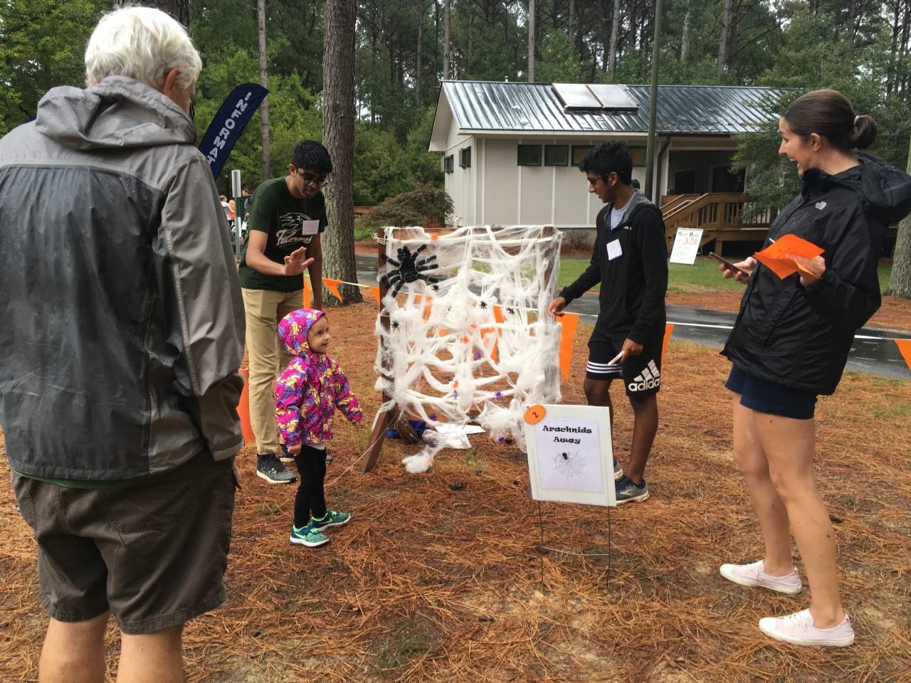 Child playing a game at Haunting at Harris event (throwing plastic spiders at a large web on a wooden frame)