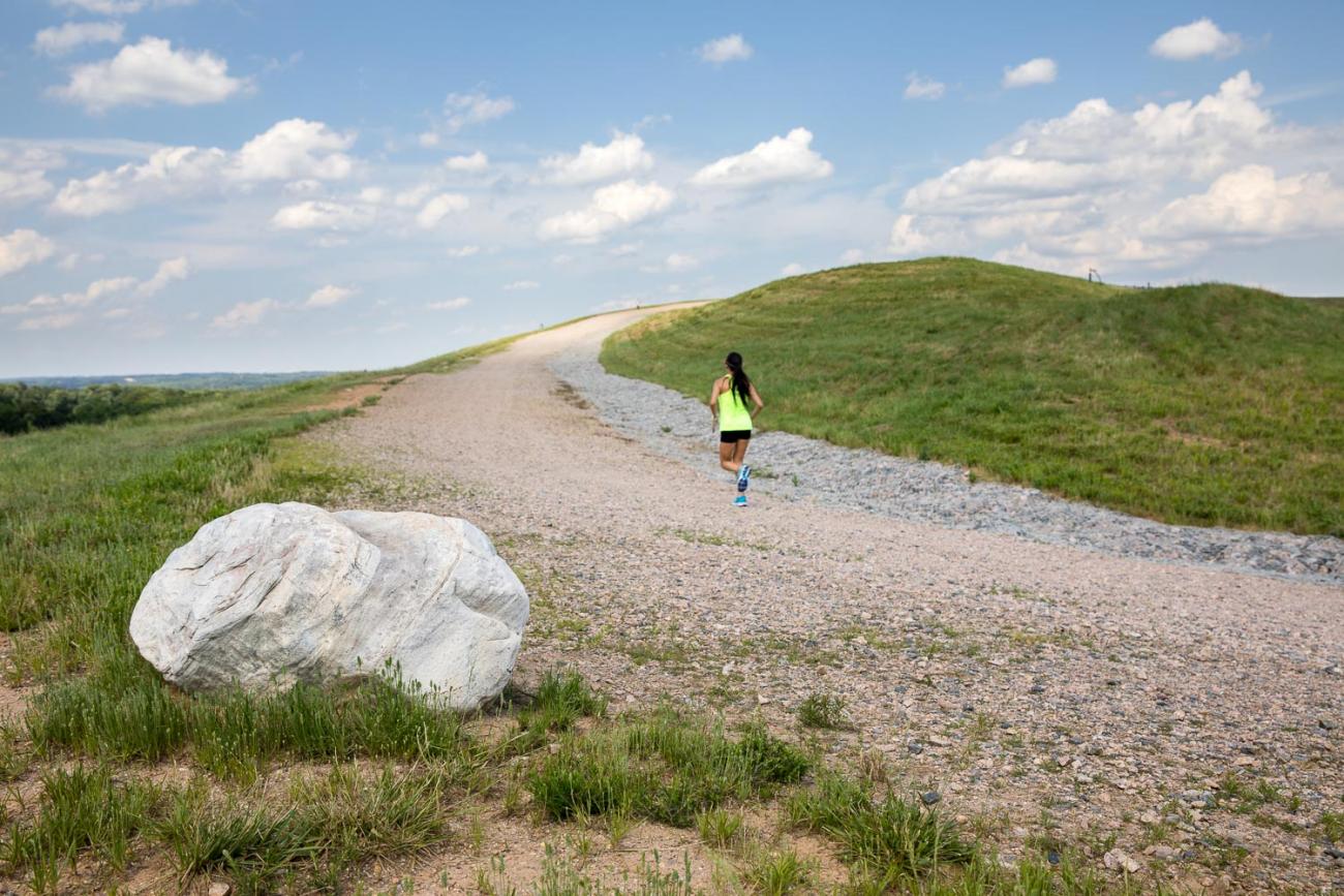 Woman running up the graveled Top of Hill Trail