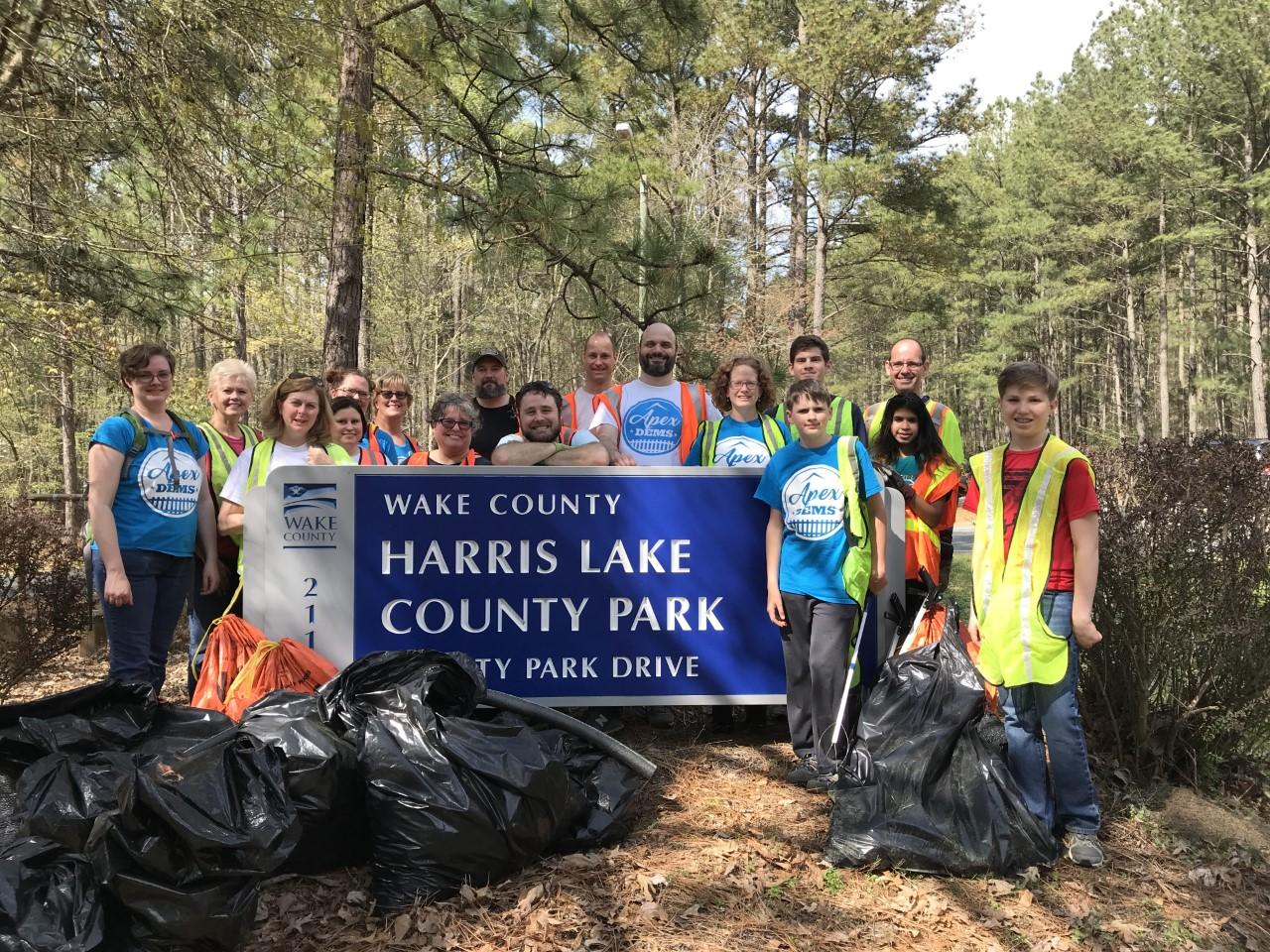 Photo of group of volunteers standing at the park entrance with collected bags of trash and debris