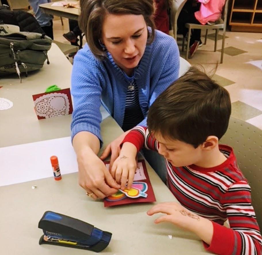 Mother and child work on valentine craft inside classroom during historical valentines day program