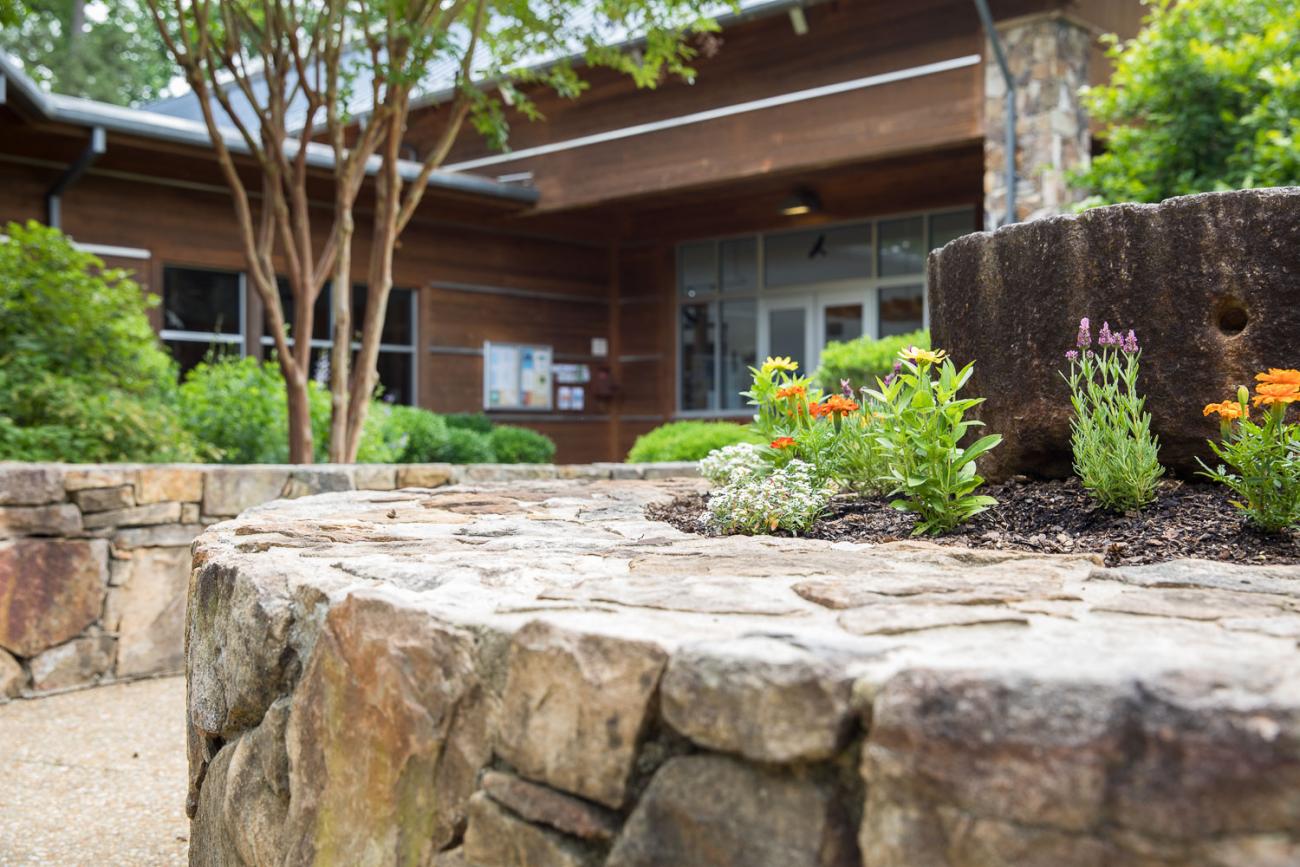 view of stone building with mill stone flower bed in front with paved stone path