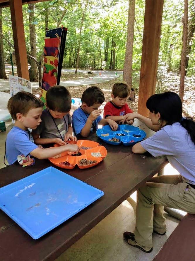 Programmer sits at picnic table with children and helps with activity