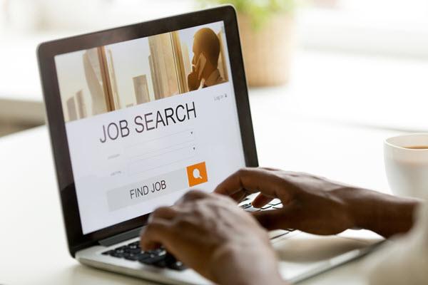 hands typing on an open laptop with job search on the screen