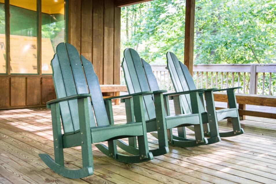 3 green rocking chairs sit underneath wooden pavilion