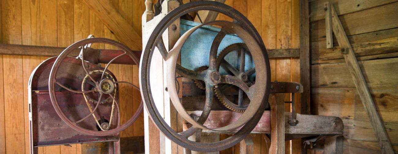 two old rusted wheel and axle machines inside old wooden mill building