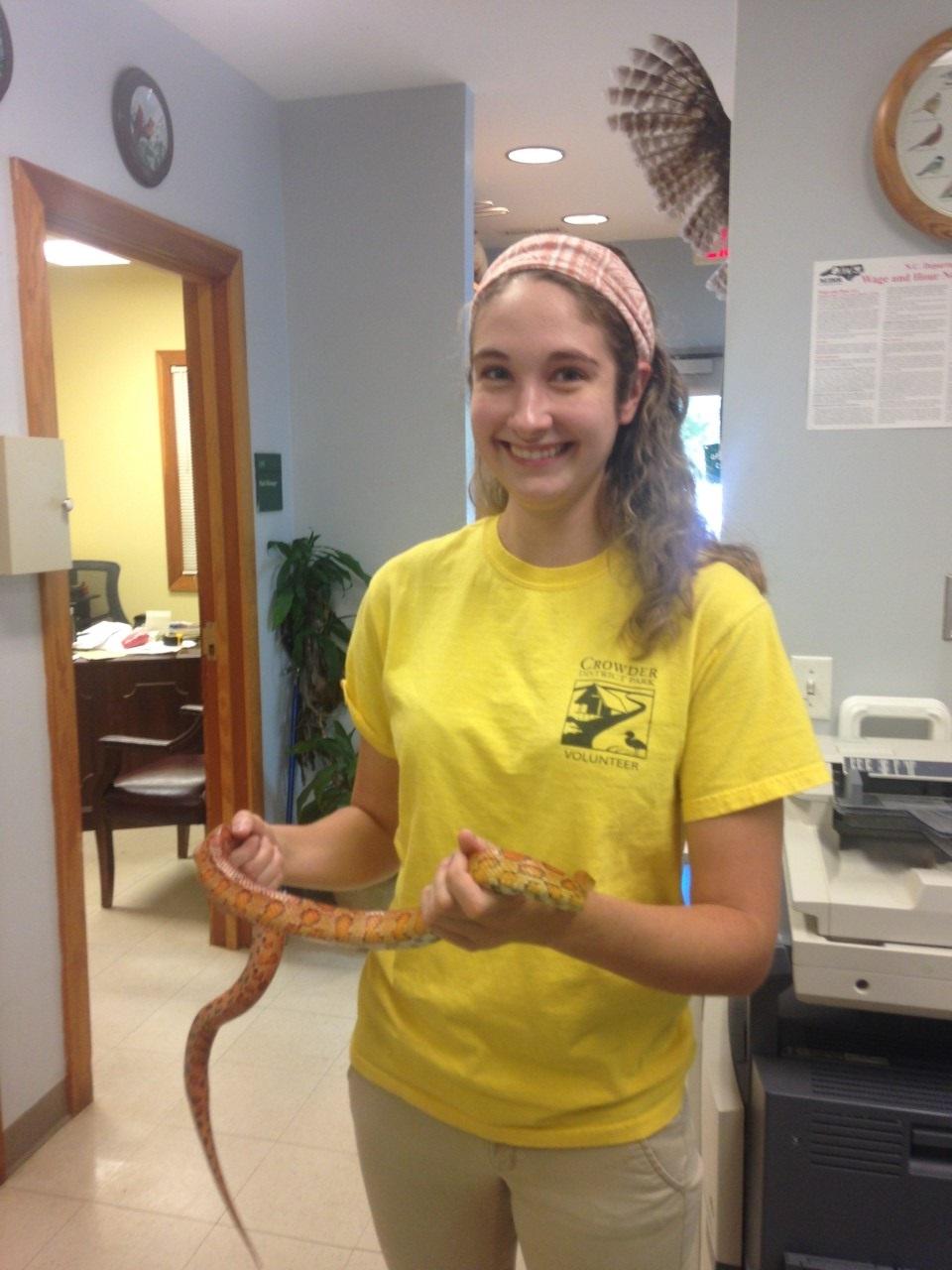 Intern stand in park office holding educational orange cornsnake