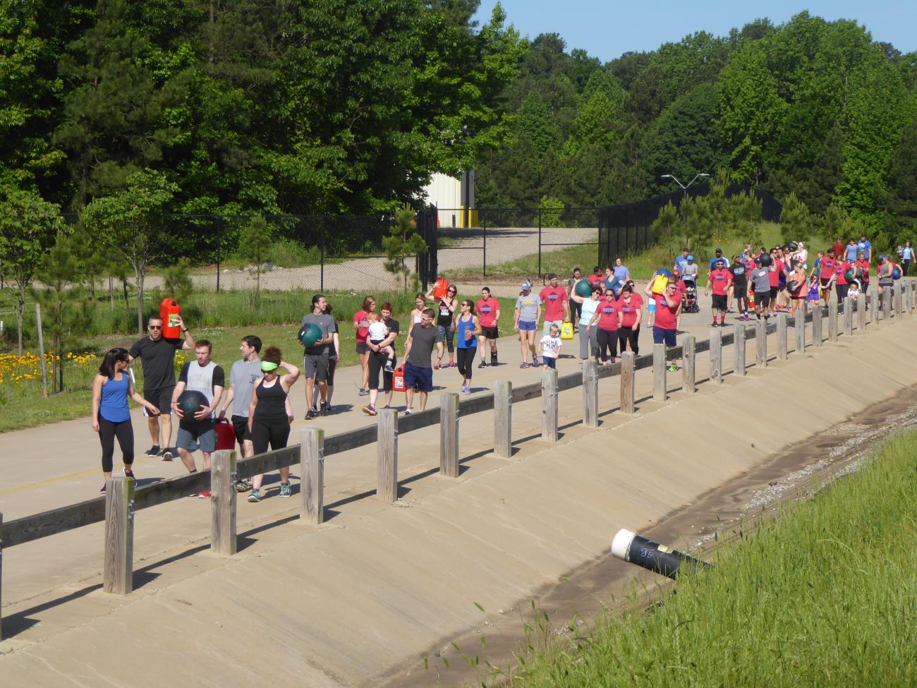 Event at Green Hills featuring a large group of people carrying items along the concrete road.