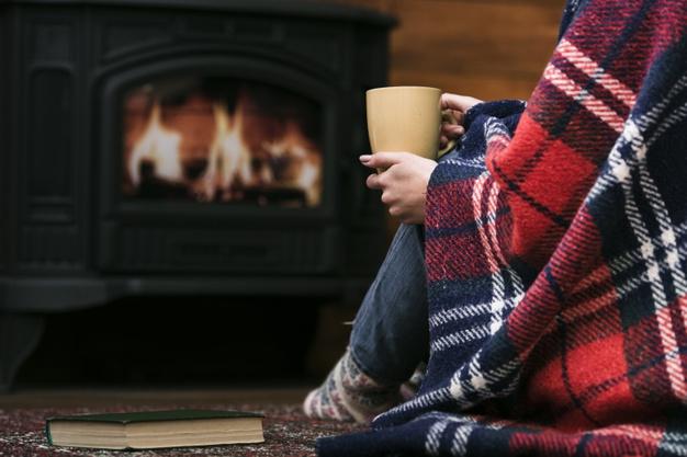 Woman sitting in front of a lit fireplace.
