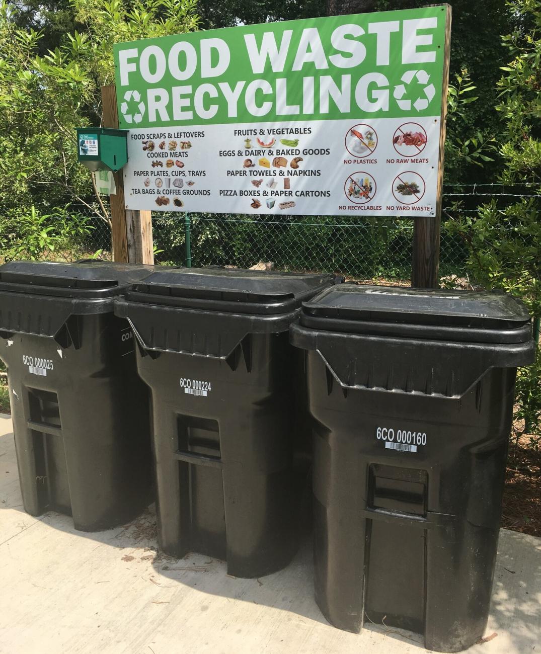 Three black carts in front of a sign that reads Food Waste Recycling.