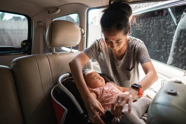 Mother securing a child in a passenger safety seat