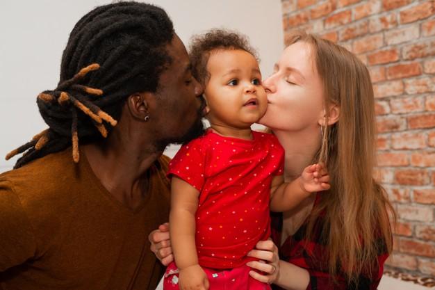 Mother and father kissing their infant child.