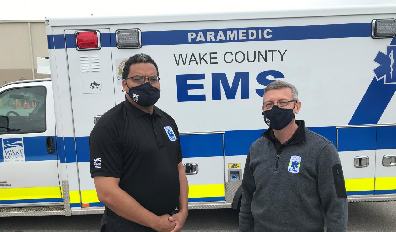 Chief Brooks and Chief Hammerstein smiling in front of ambulance.