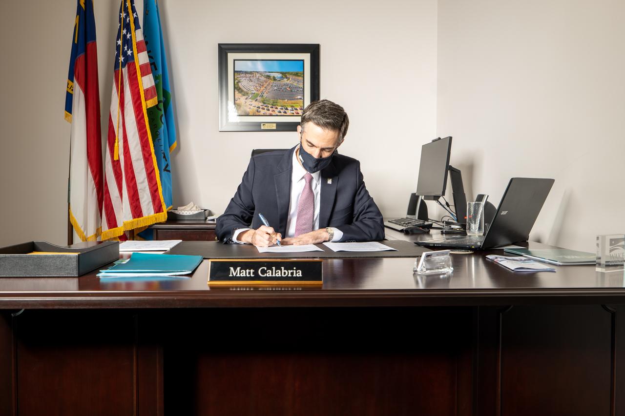 Commissioners Chair Matt Calabria signs mask mandate at his desk