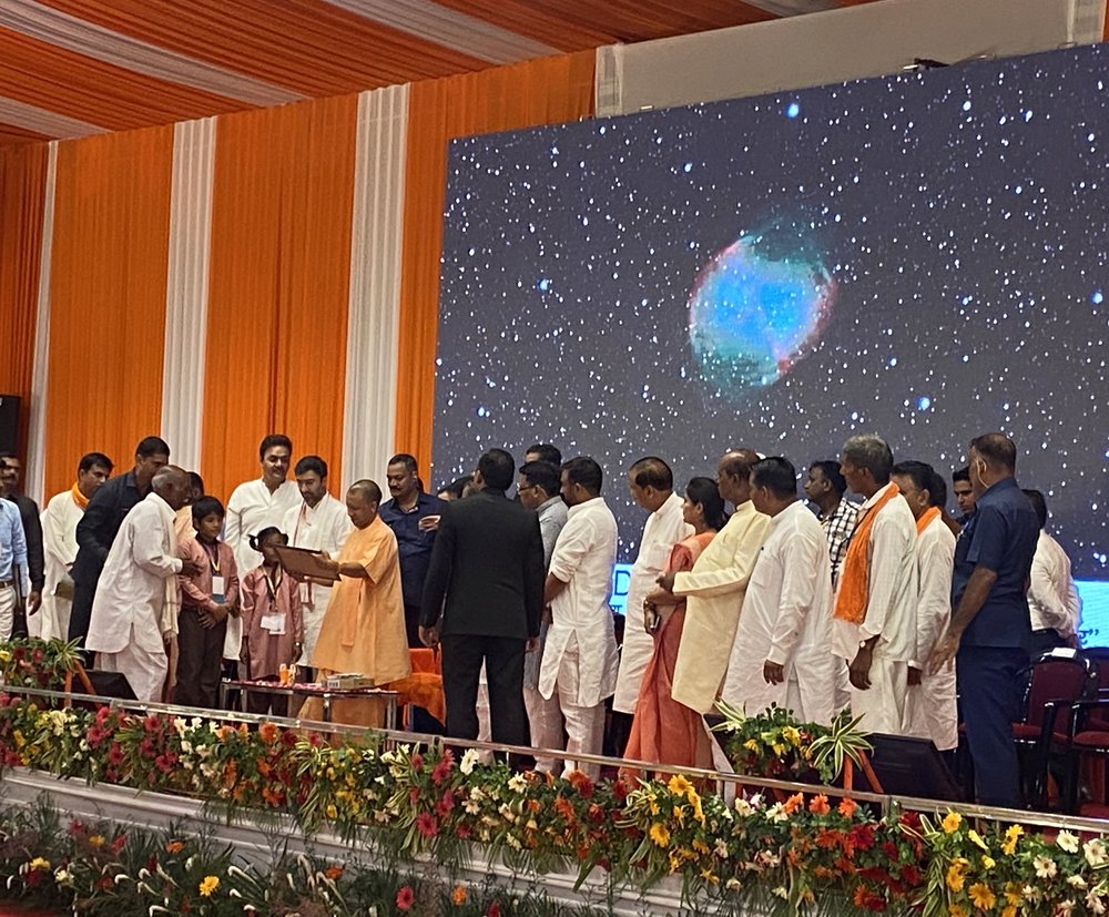 Mission Platinum students and their families being presented with a certificate of achievement. The backdrop is a picture taken by the student of M57, the Dumbbell Nebula, using LCO.