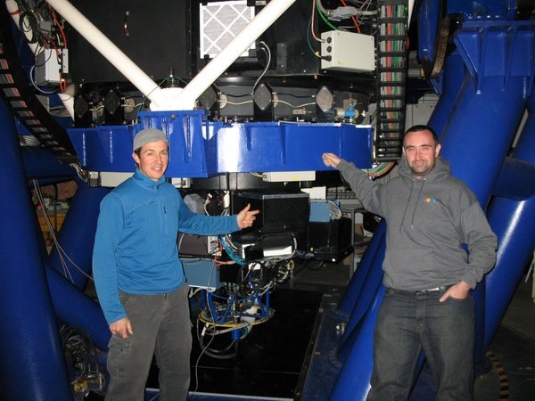Photo of two scientists stood next to a spectrograph on LCO's 2-meter telescope