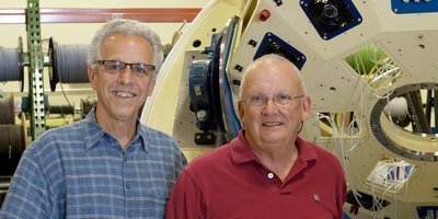 Las Cumbres Observatory Director Todd Boroson and Founder Wayne Rosing, in the LCO warehouse with the mount for a 1-meter telescope. (Photo credit Paul Clay.)